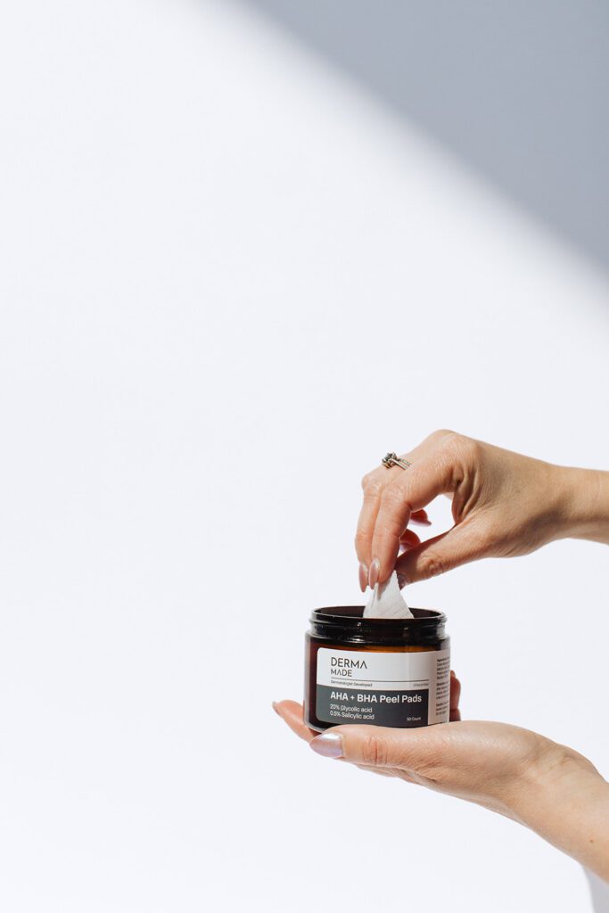 ONYX Beauty Lab | The Onyx Beauty Lab 2025 Holiday Gift Guide A hand pulls out a pad from a container of Derma Made AHA + BHA Peel Pads.