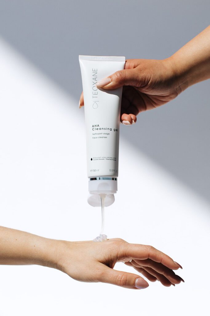 ONYX Beauty Lab | The Onyx Beauty Lab 2025 Holiday Gift Guide A woman extends her hand underneath a product, Teoxane Cleansing Gel.
