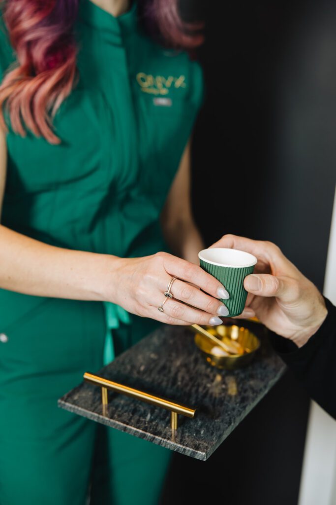 ONYX Beauty Lab | The Onyx Beauty Lab 2025 Holiday Gift Guide A person hands another person a cup of tea.